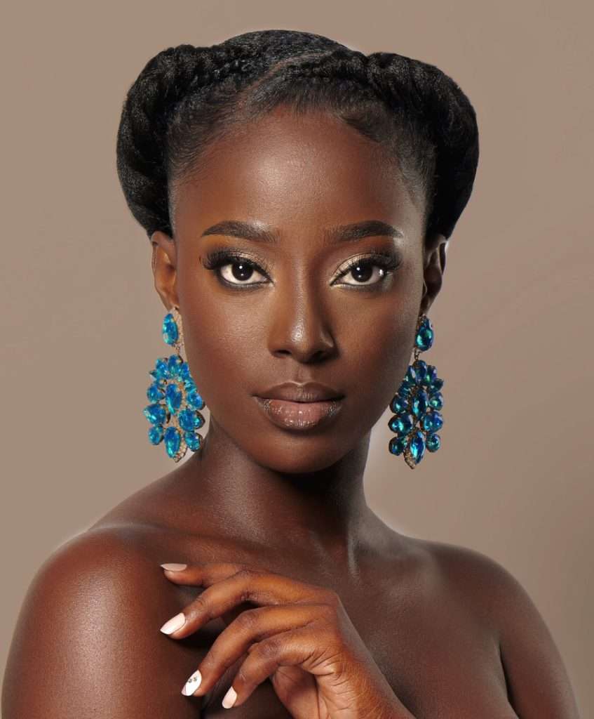 Close-up photo of Tara Richardson wearing bright blue statement earrings and natural makeup, posing against a neutral background.